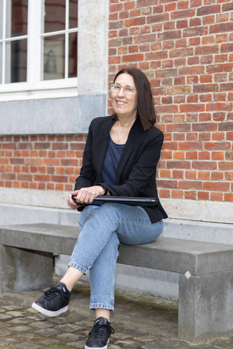 Wendy zit buiten op een bank, met de laptop op haar schoot, goed op tijd voor haar opdracht